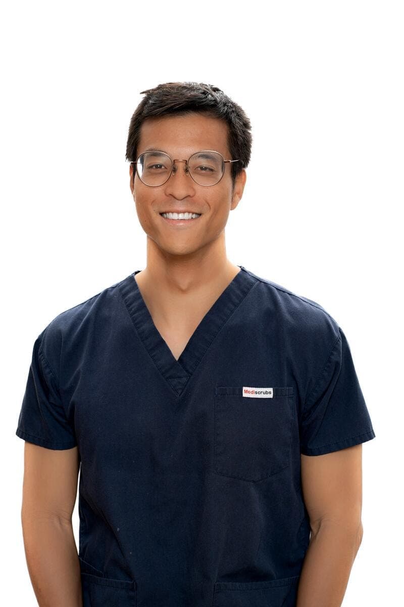 Dr John Huang, Associate Dentist at Joyner Family Dental, smiling in navy scrubs