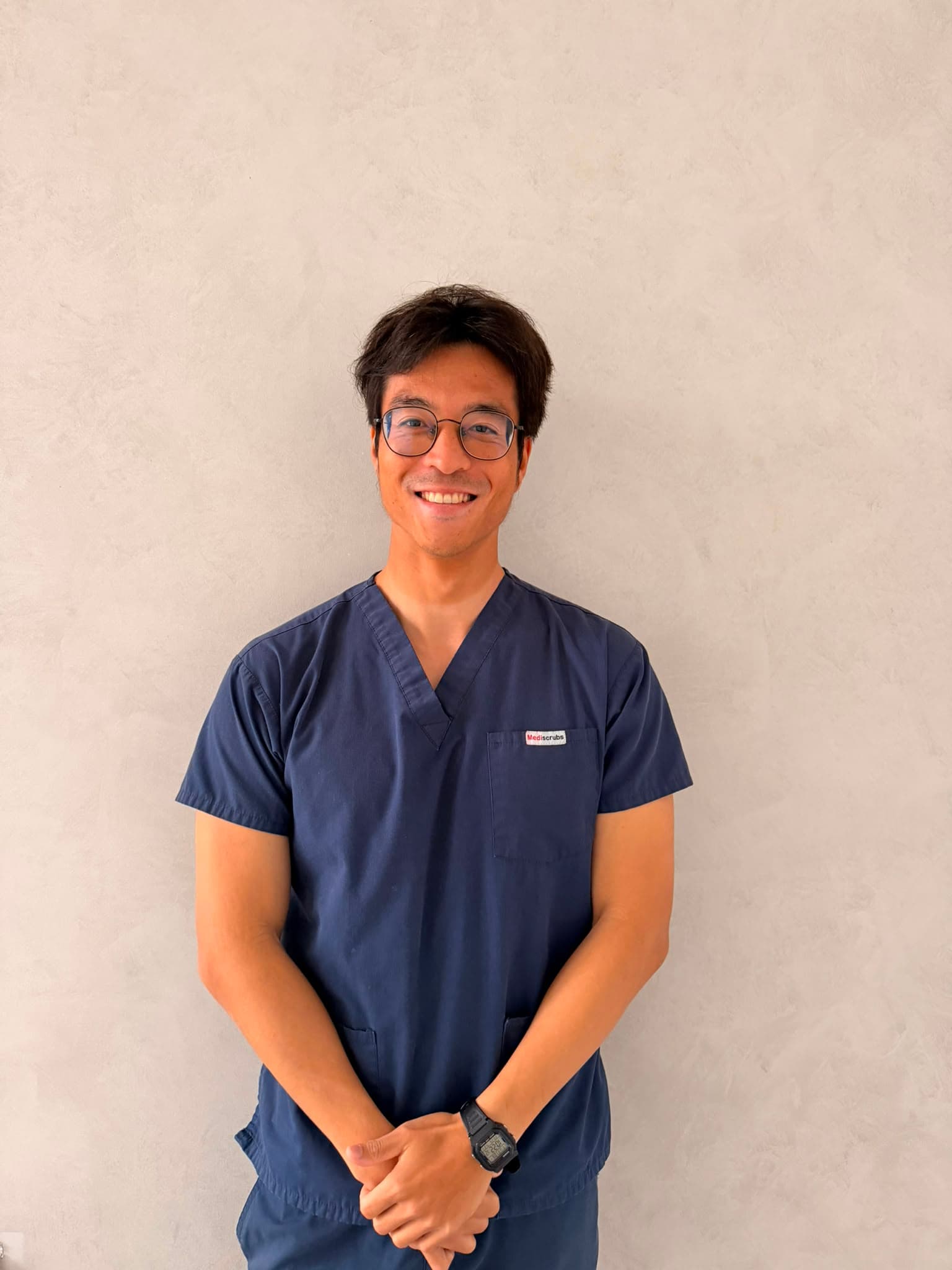 Dr John Huang, Associate Dentist at Joyner Family Dental, smiling in navy scrubs
