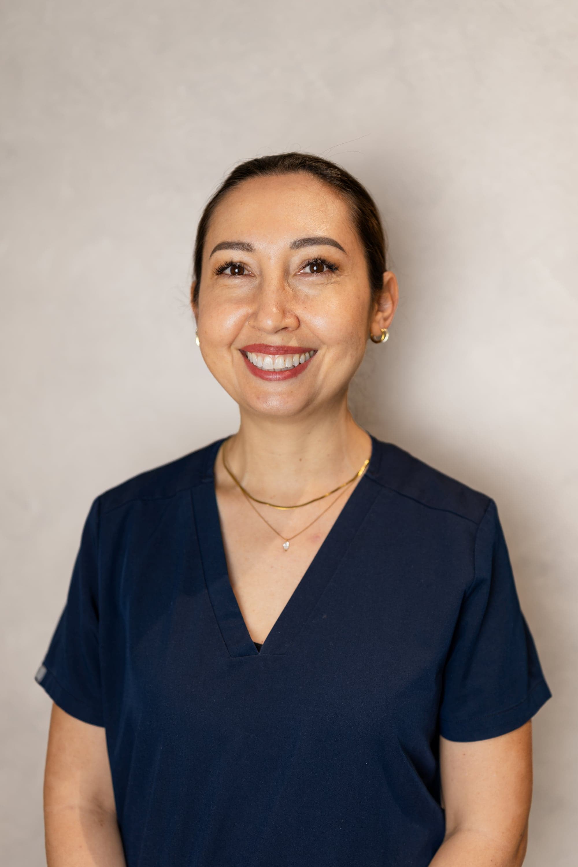 Dr Natasha Golingi, Associate Dentist at Joyner Family Dental, smiling in blue scrubs