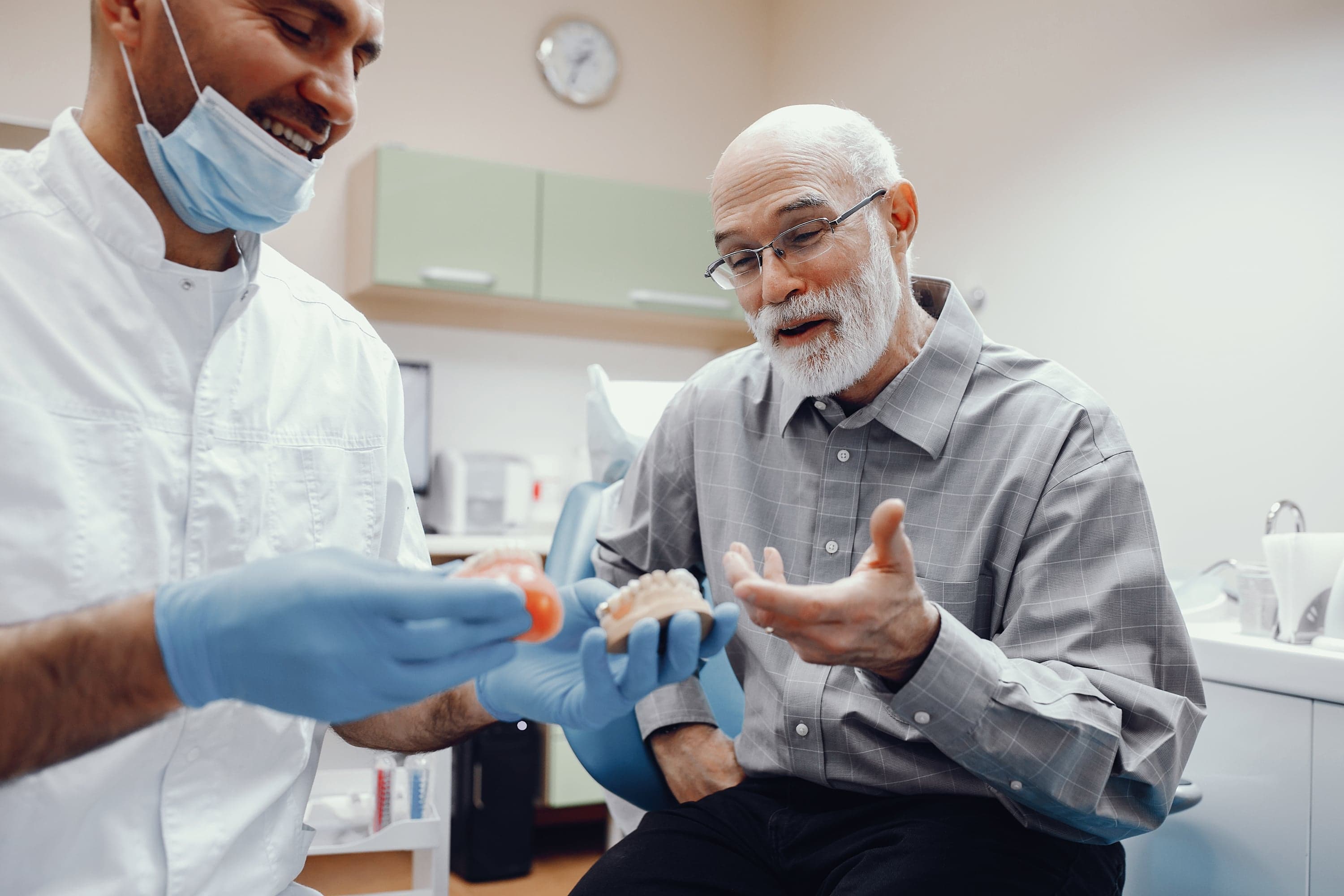 Dentist examining a custom denture while reassuring a patient at Joyner Family Dental