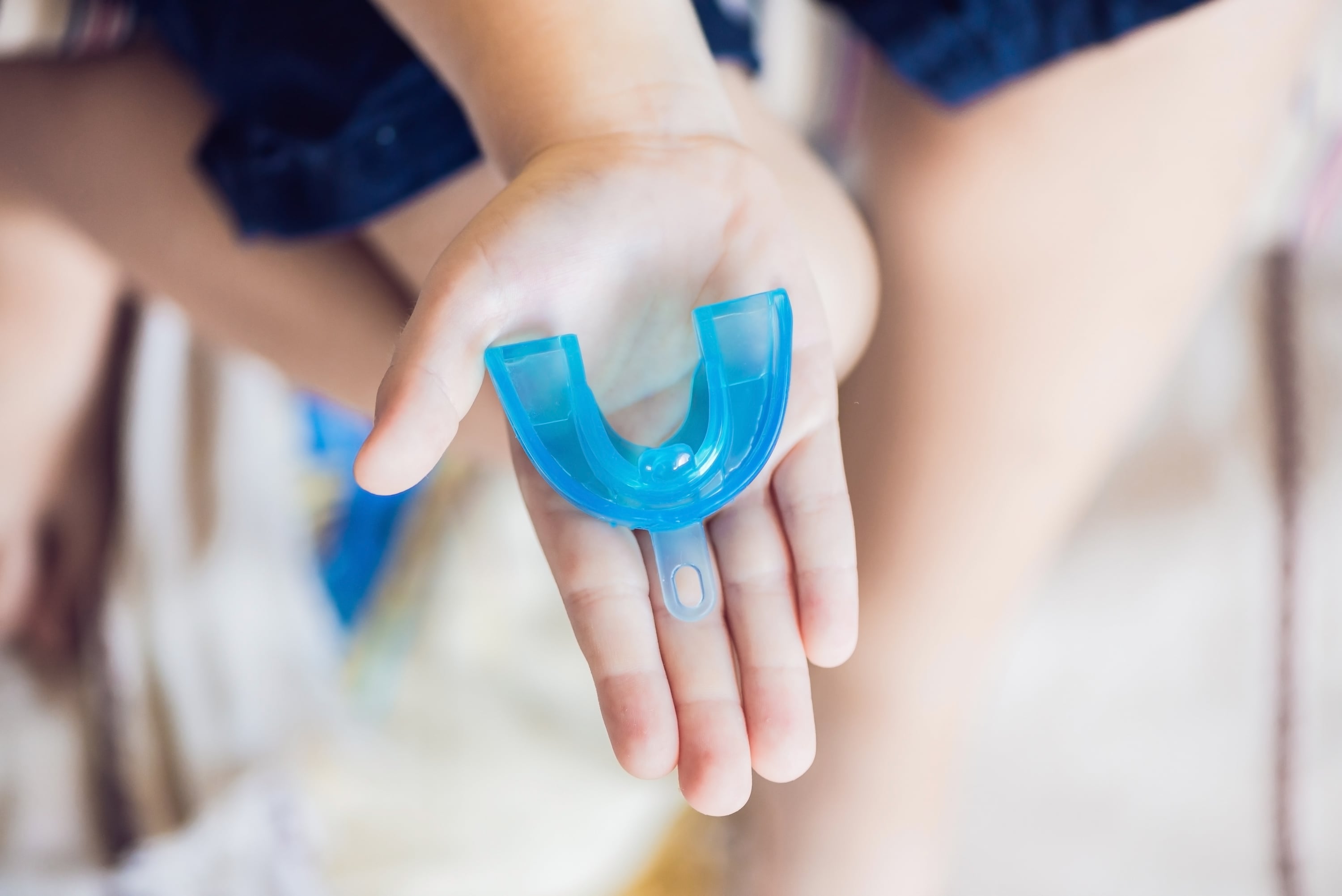 Teen athlete holding a custom mouthguard case after training